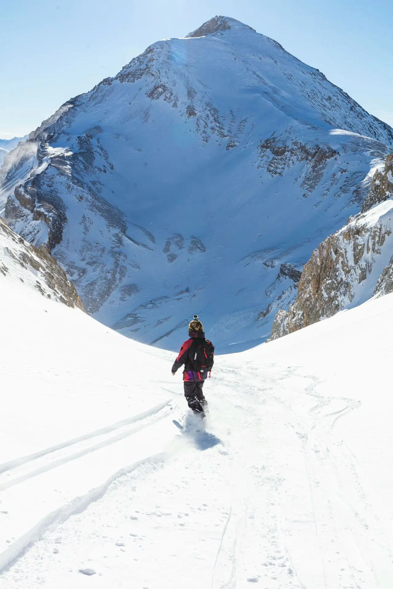 man in black jacket and black pants walking on snow covered mountain during daytime